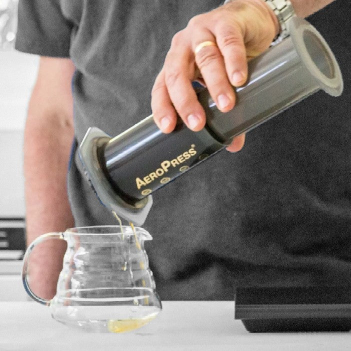 AeroPress being flipped upside down and fitted atop a glass carafe. 