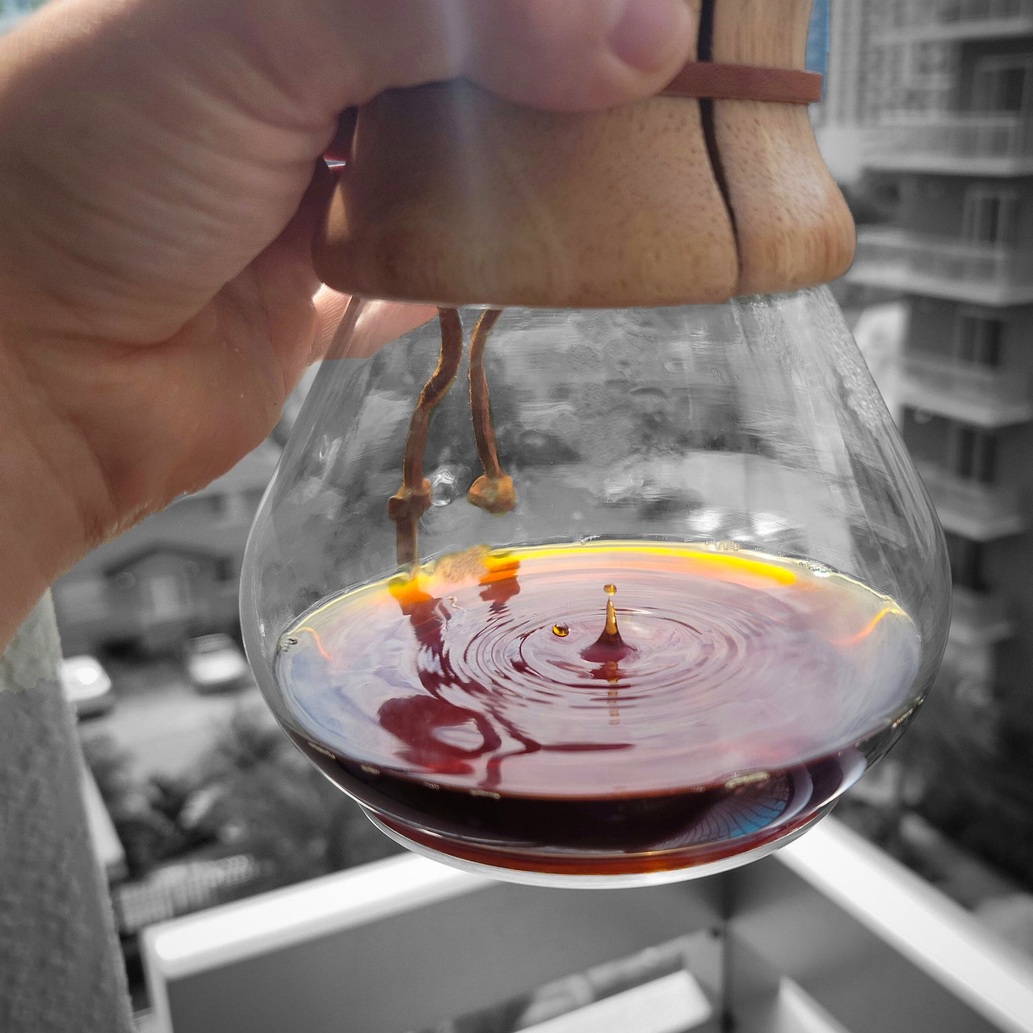 Close up of the bottom of a Chemex coffee maker with drops of coffee dripping from the top filter. 