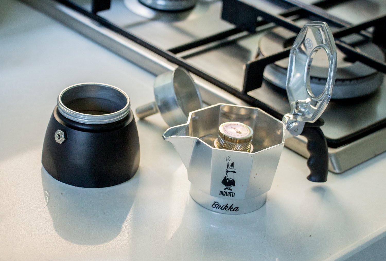 Image of Bialetti Brikka disassembled, next to a gas stove. 