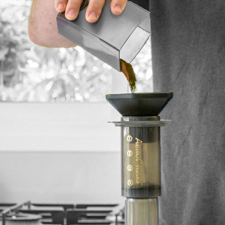 Coffee being poured inside an AeroPress coffee maker. 